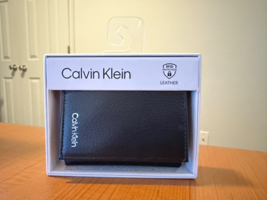 Billetera Calvin Klein color negro de cuero genuino con protección RFID, diseño plegable, múltiples compartimentos para tarjetas y billetes, presentación original en caja, ideal para uso diario o regalo.