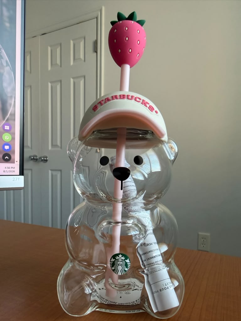 Vaso Bearista Starbucks de vidrio transparente con diseño de oso, incluye tapa tipo gorra y sorbete reutilizable con detalle de fresa. Ideal para bebidas frías y para coleccionistas de Starbucks.