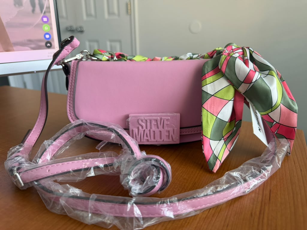 Steve Madden. Cartera de hombro color rosa con cierre superior, correa ajustable y removible, logo frontal y pañuelo decorativo.