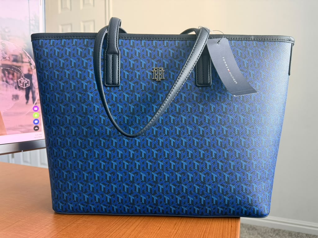 Tommy Hilfiger. Bolso tote color azul con estampado monograma, doble asa de hombro, amplio compartimento principal y logo metálico frontal.
