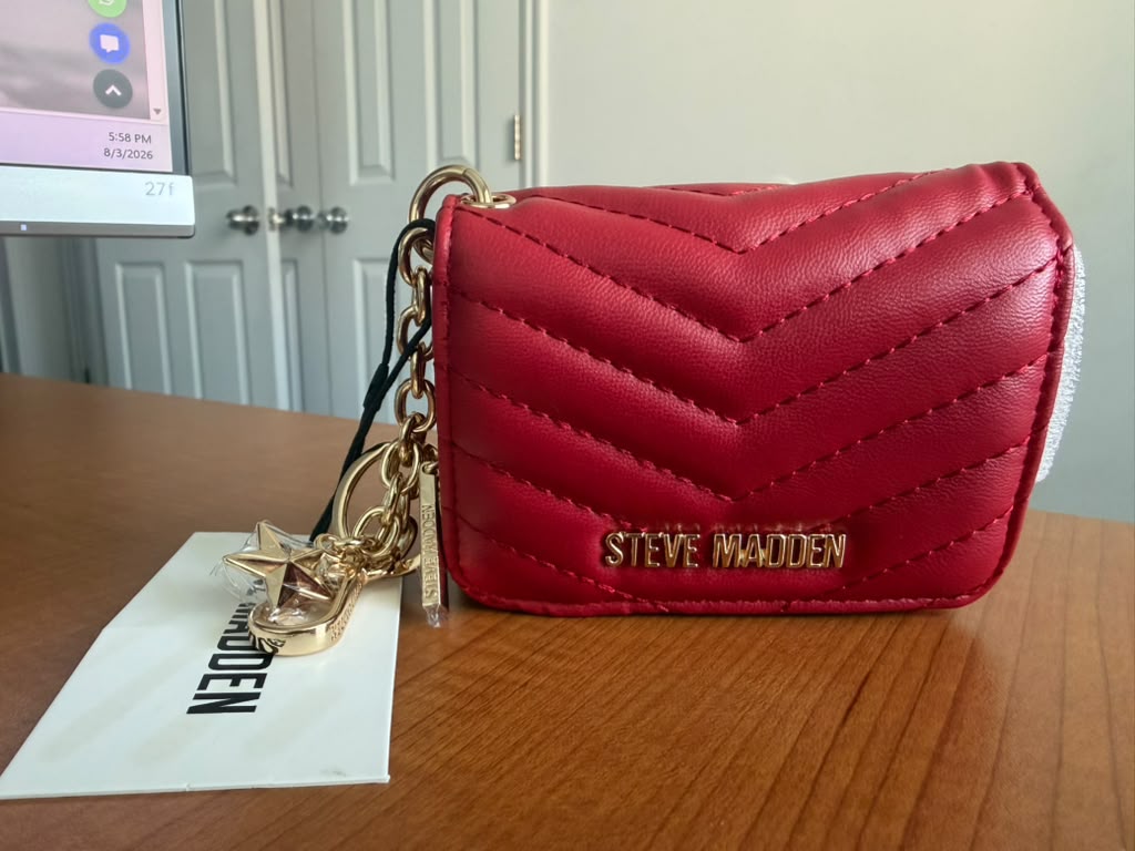 Steve Madden. Billetera acolchada color rojo, diseño acolchado en patrón chevrón, cierre con broche, logo metálico y llavero decorativo.